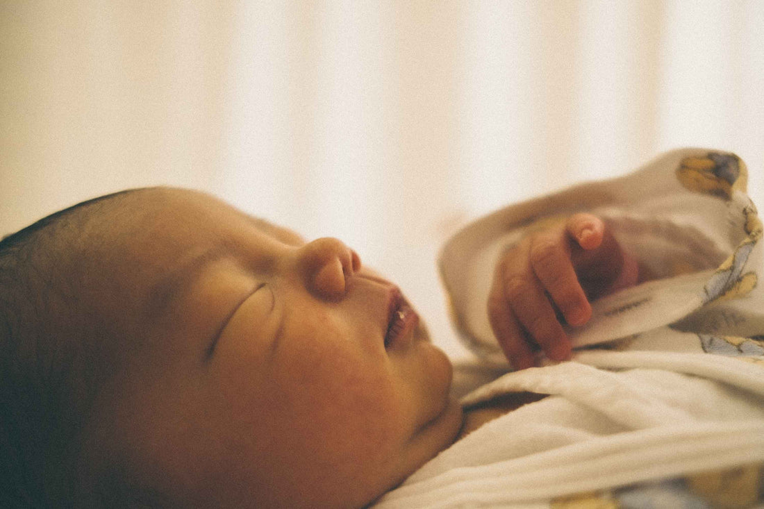 Newborn baby sleeping peacefully nestled in soft white blankets