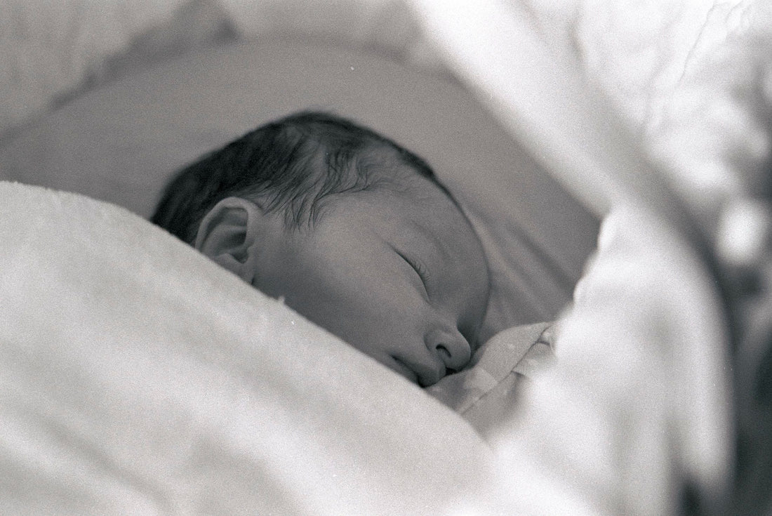 Newborn baby lying peacefully on their back with hand raised