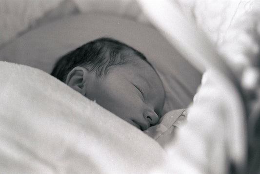 Newborn baby lying peacefully on their back with hand raised