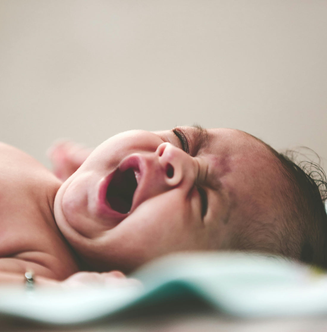 Close-up of a crying newborn baby lying down