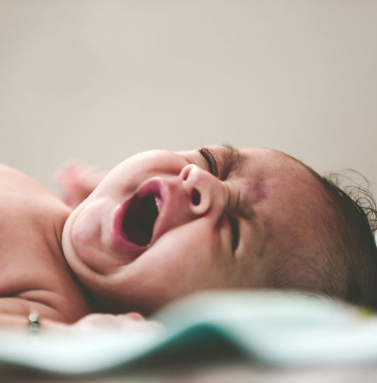 Close-up of a crying newborn baby lying down