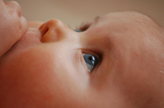 Close-up of a baby girl in a pink outfit being held by her mother