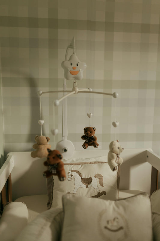 Cosy nursery crib with teddy bear mobile and soft lighting